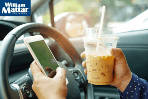 person drinking cold coffee drink while texting while behind wheel driving