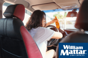Woman drinking a bottle of beer while driving