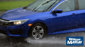 blue car hydroplaning on wet road